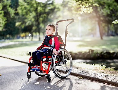 Beautiful little boy on wheelchair in the park
